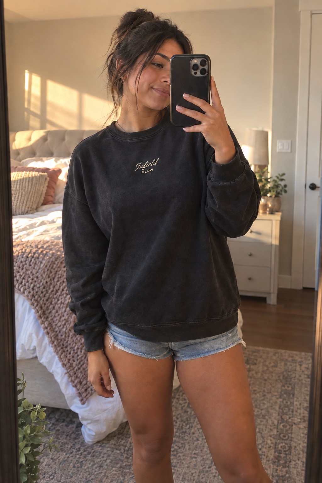a girl taking a mirror photo in her bedroom before heading out, phone half covering her face, soft daylight